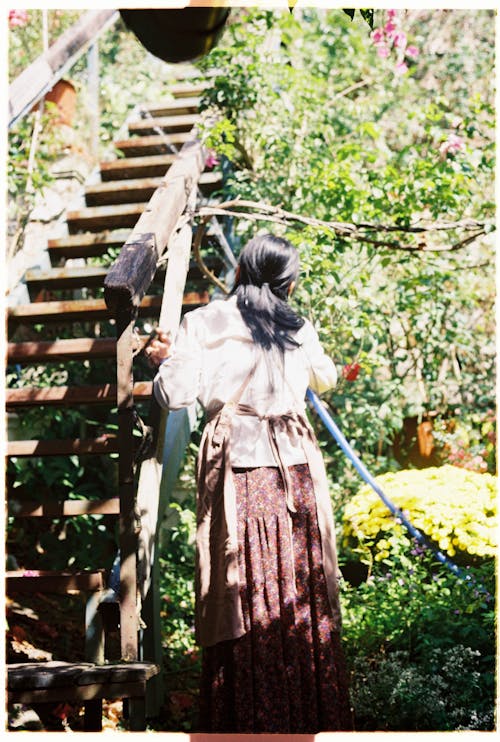 A woman in a long dress is standing on a wooden staircase