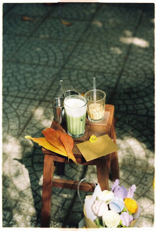 A small table with a glass of juice and a flower