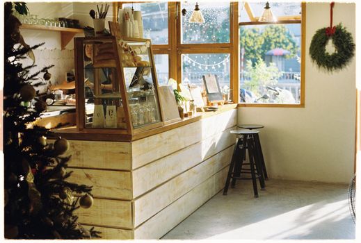Warm café setting with festive wreath and wooden counter by a bright window.