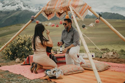 A couple sitting on a blanket under a tent
