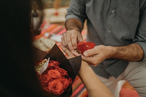 A man is putting a red rose into a woman's hand