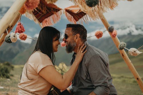 A couple sitting under a tent with colorful pom poms