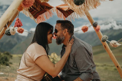 A couple sitting under a tent with colorful pom poms