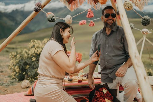 A couple sitting on a picnic table with a tent