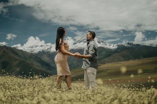 A couple holding hands in a field with mountains in the background
