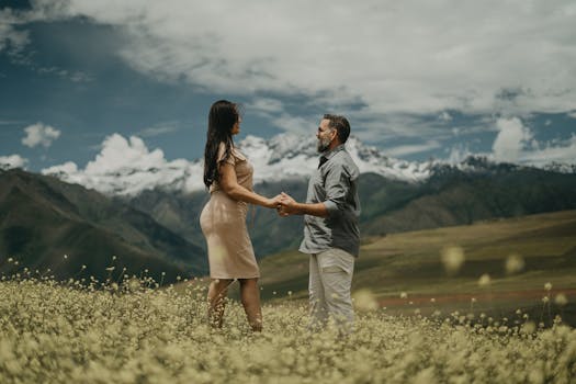 A couple standing in a Maras, Peru meadow, framed by majestic mountains, embracing love and nature.