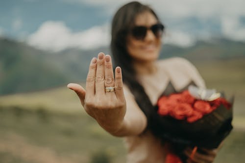 A woman holding a bouquet of flowers and a ring