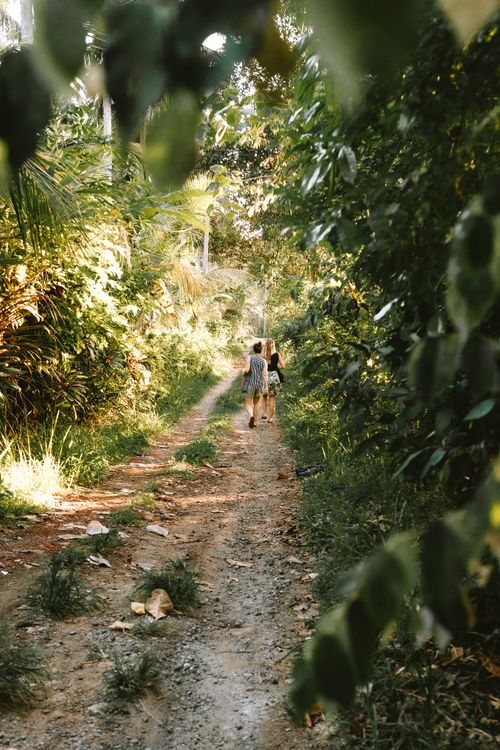 Free Two women strolling through a lush green path in rural Bali. Stock Photo