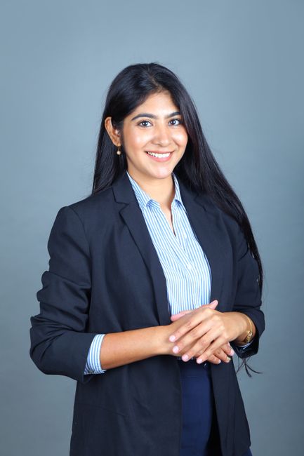 Confident woman in business suit smiling with a formal pose against a neutral background