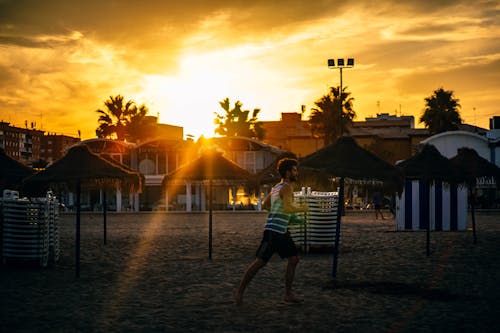 免費 男人在日落期間在海灘上運行 圖庫相片