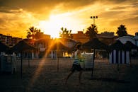 日落时分，温暖的阳光洒在瓦伦西亚海滩上，一名男子正沿着海岸慢跑