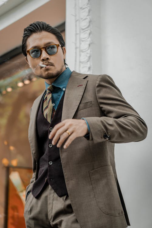 Asian Man in a Business Attire and Glasses Smoking a Cigarette