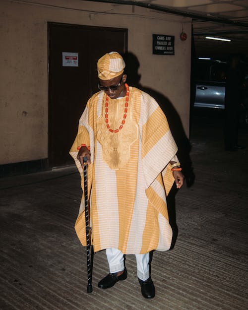 A man in an african outfit walking down a street