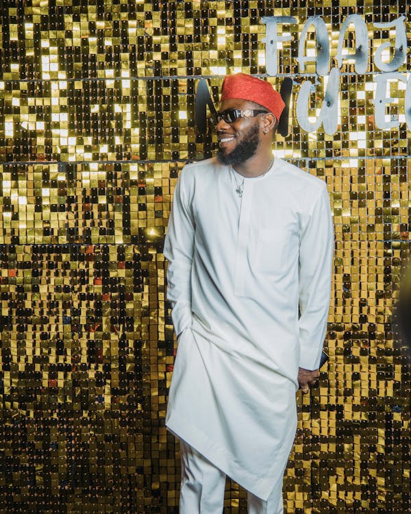 A man in a white hat and red pants standing in front of a gold wall