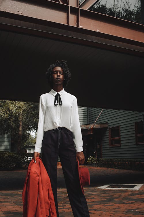 Elegant woman in a White Shirt and Black Trousers Standing Outside 