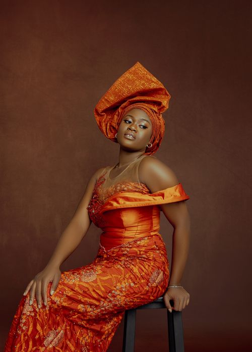 Free Portrait of a woman in elegant traditional orange clothing, sitting gracefully. Stock Photo