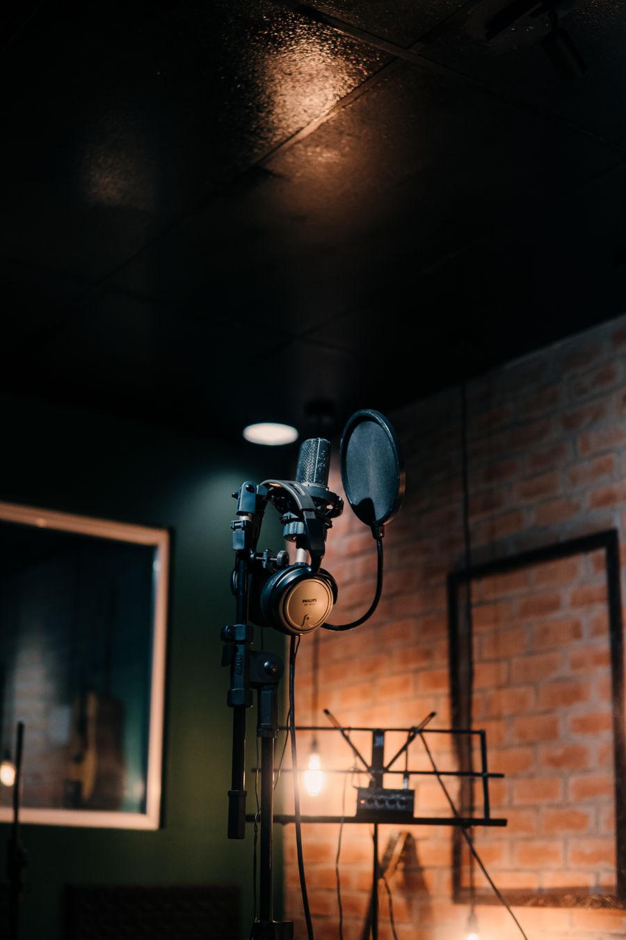 Microphone and headphones on a stand in a dimly lit recording studio