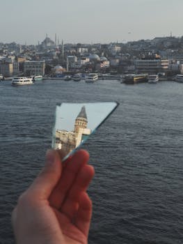 Artistic reflection of Galata Tower in a hand-held mirror over the Bosphorus in Istanbul.