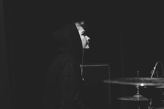 Captivating black and white side view portrait of a drummer under spotlight on stage.