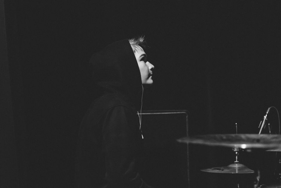 Captivating black and white side view portrait of a drummer under spotlight on stage.