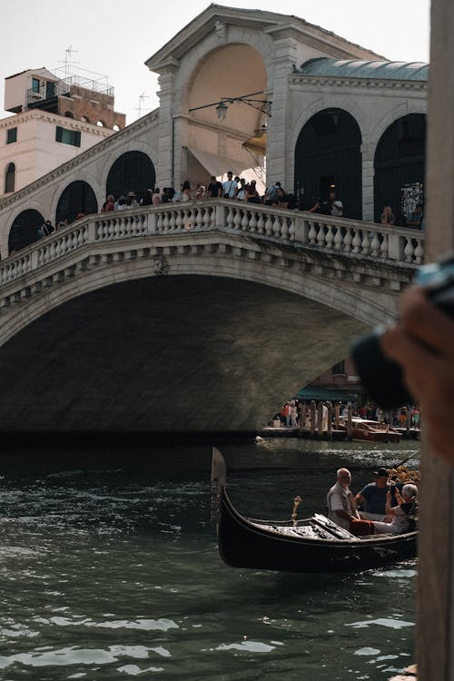 A gondola is being pulled by a boat under a bridge