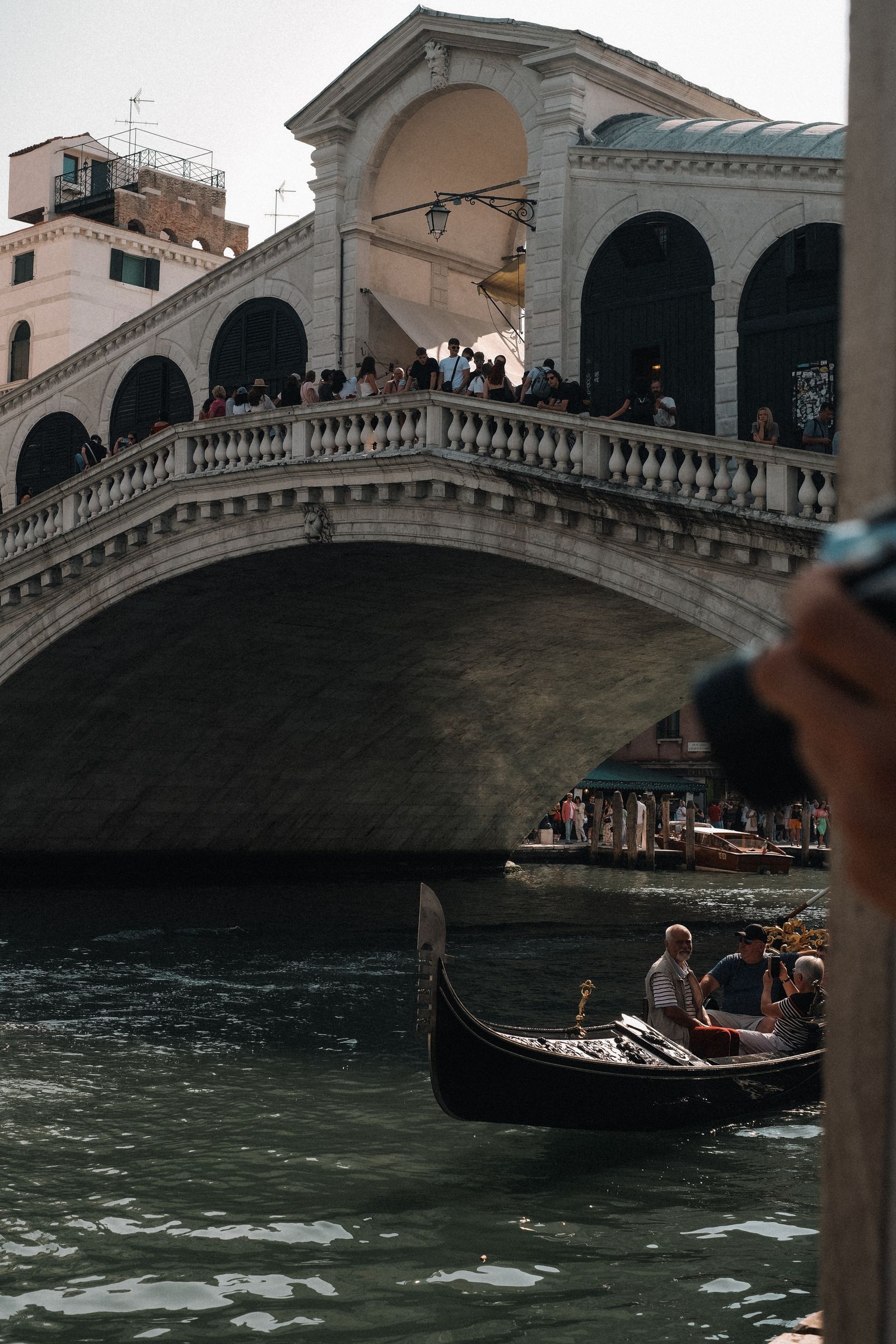 Gondola gliding under the Rialto Bridge on a sunny day in Venice, one of the destinations rolling out new tourist taxes in 2026