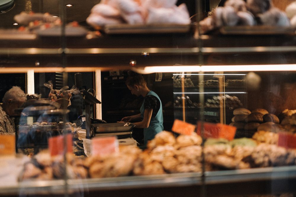 Personal de cafetería atendiendo el mostrador con productos expuestos.