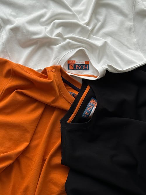 Three t - shirts with orange, black and white