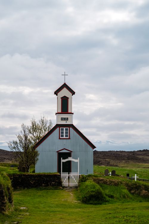 Free A scenic view of a historic wooden church and cemetery in the countryside. Stock Photo