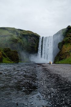 Captivating view of the Skogafoss waterfall, a stunning natural landmark in Iceland, with tourists in the foreground.