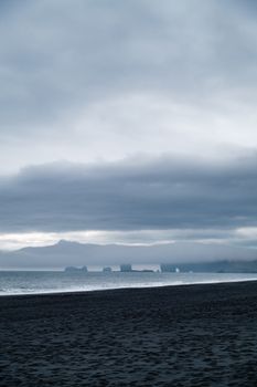A serene beach with a dramatic overcast sky and dark sea, creating a moody scenery.