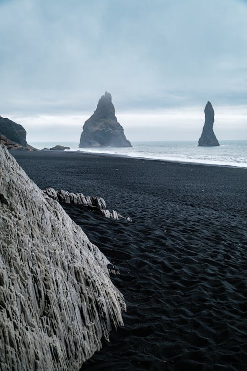 Black sand beach with two rocks in the distance