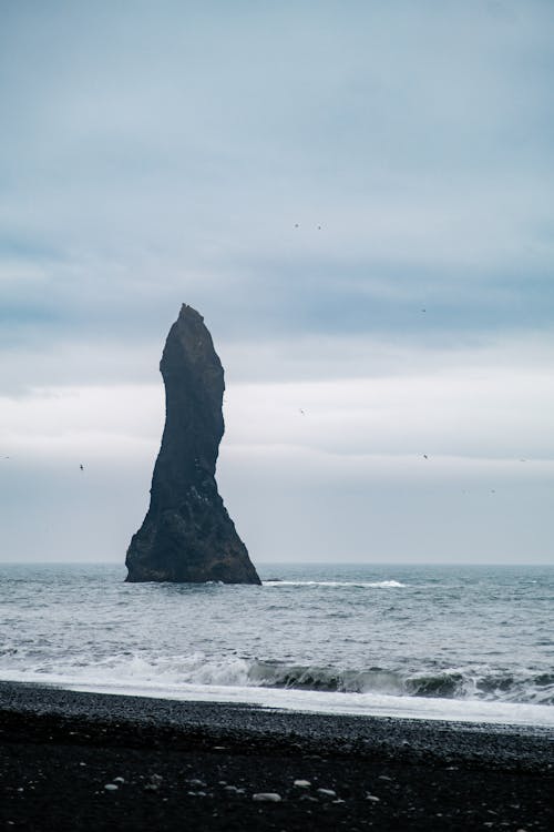 A black rock in the ocean with waves