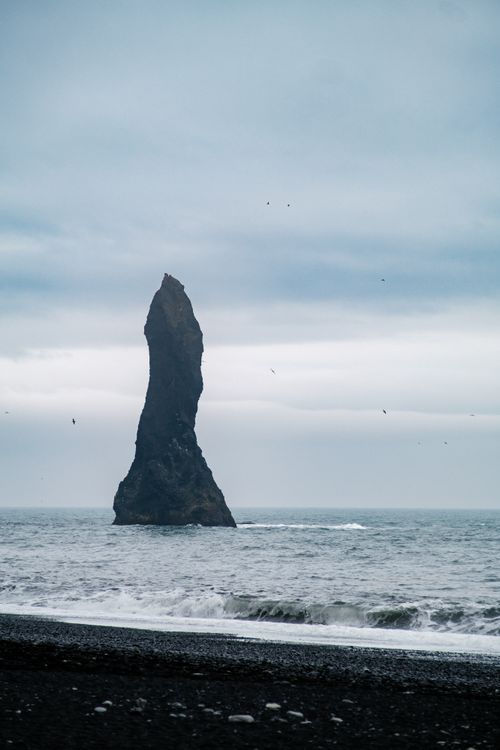 Free Stunning sea stack at Reynisfjara Beach, Iceland with moody skies and ocean waves. Stock Photo