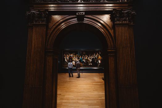 Two adults view a historic painting in Amsterdam museum's art exhibit.