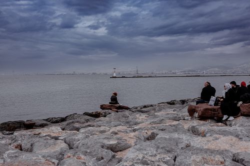 Free People enjoying a cloudy day by the rocky seashore in Izmir, Turkey. Stock Photo