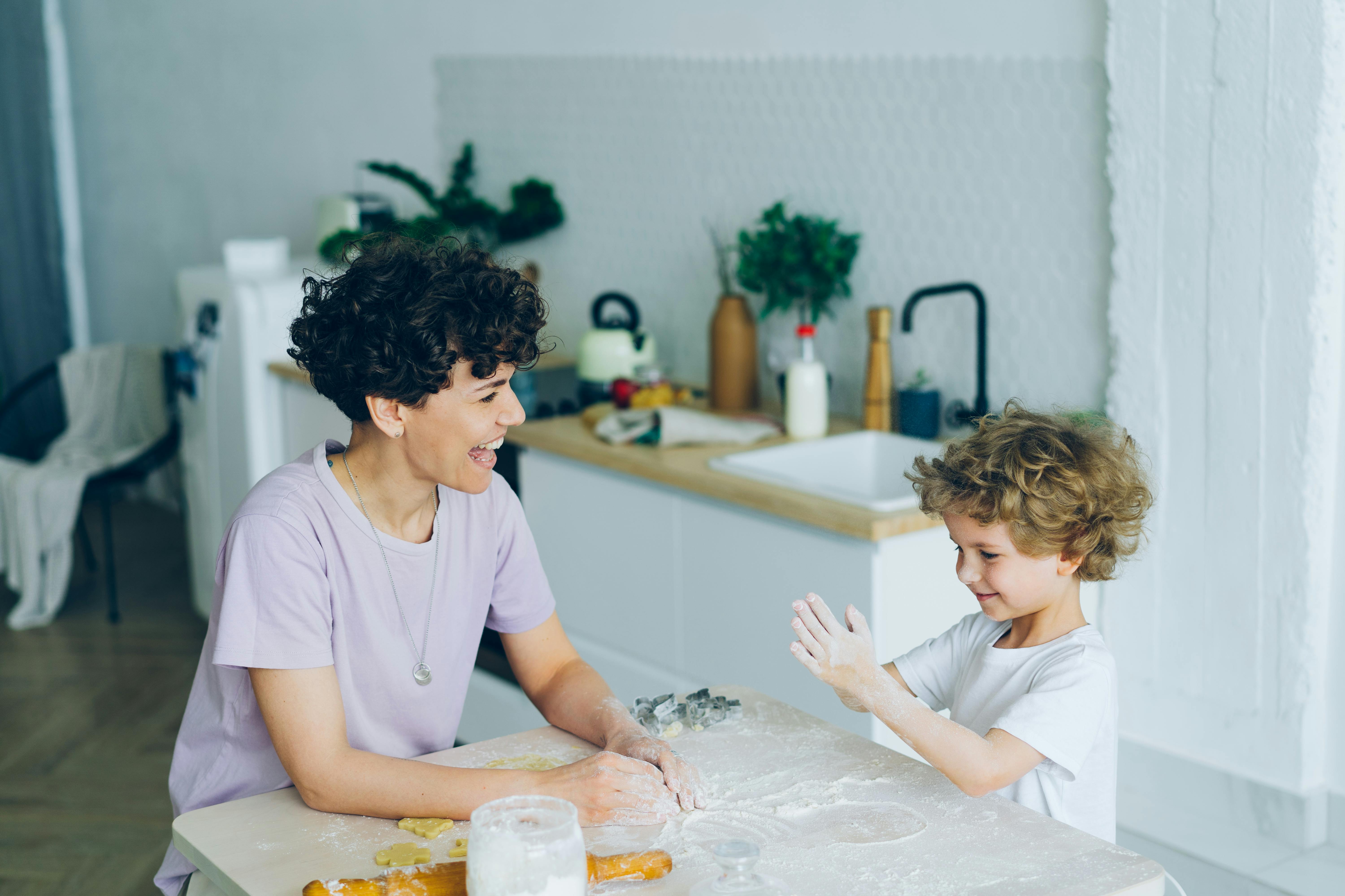 smiling mother and son playing on table in kitchen