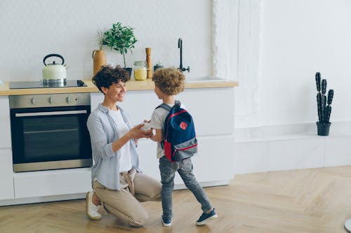 Smiling Mother and Son with Backpack in Kitchen