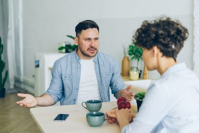 Two people talking across a kitchen table — Vitaly Gariev on Pexels