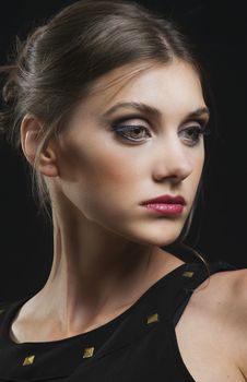 Sophisticated studio portrait of a woman with makeup on a black background.