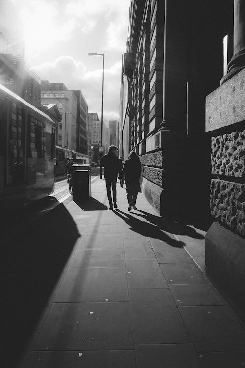 A black and white photo of two people walking down a street