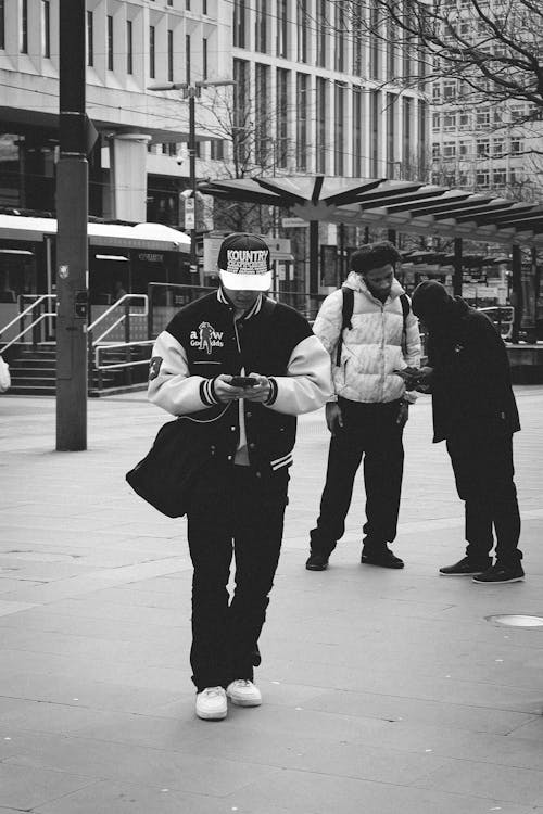 A man in a hat and jacket is looking at his phone