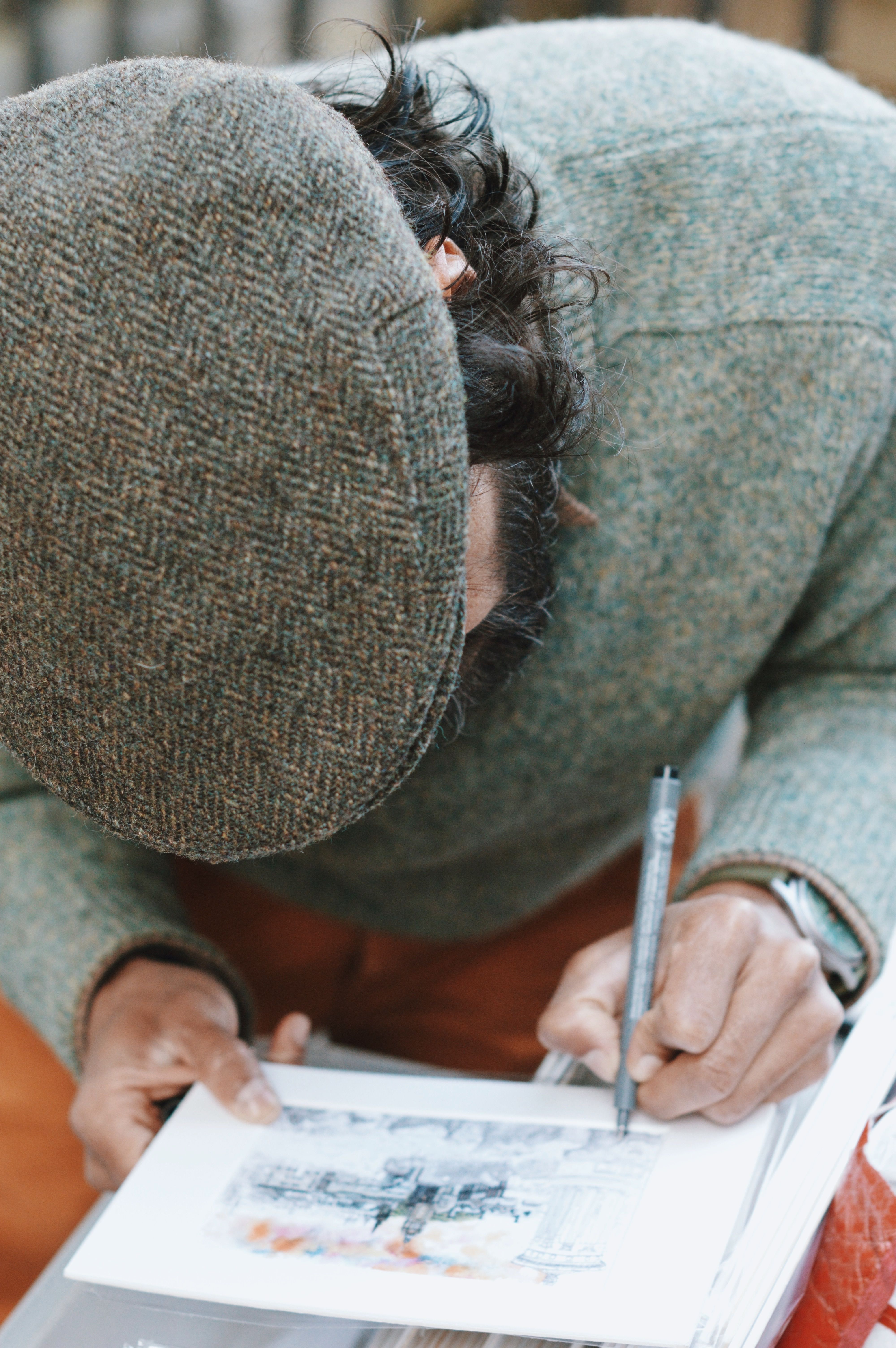 Artist drawing Edinburgh Castle outdoors in detailed sketch. Captures creative process.