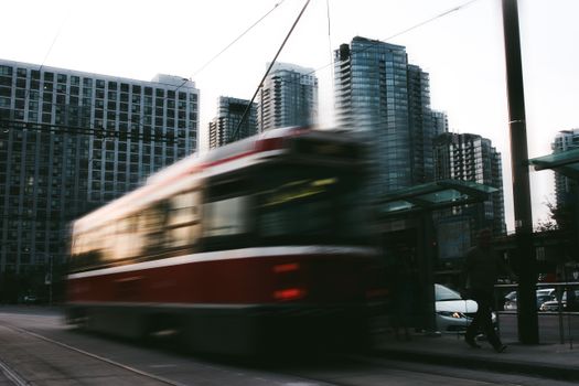 Blurred motion of a tram rushing through a modern urban landscape with skyscrapers.