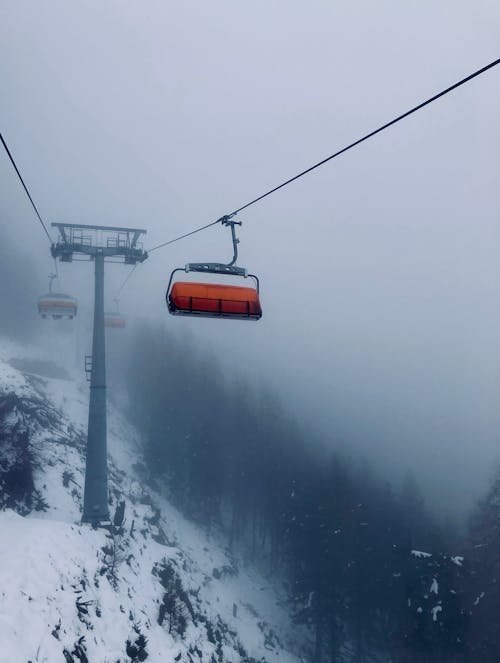 A ski lift is suspended in the fog