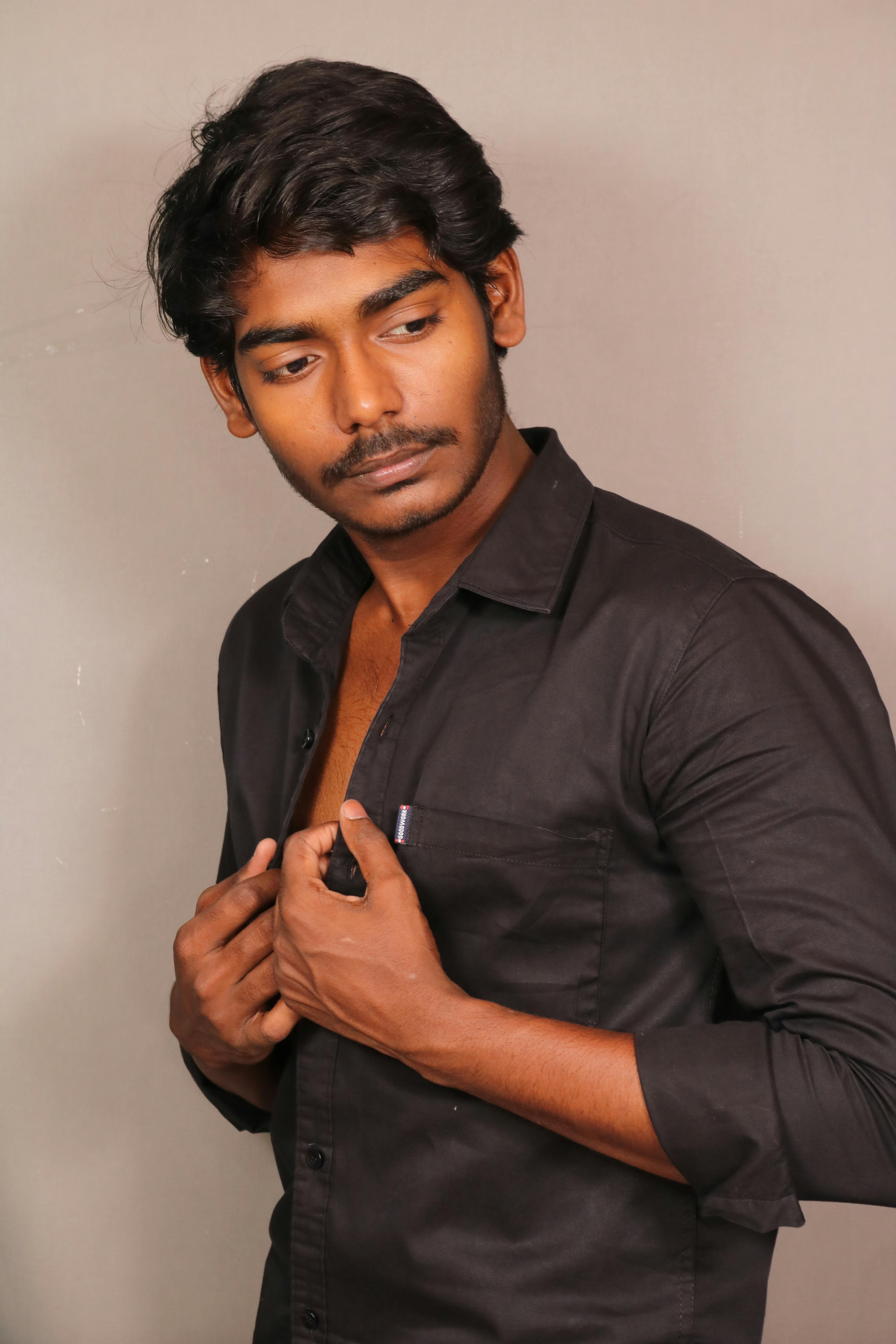 Elegant portrait of a young man in a black shirt, posing with confidence.