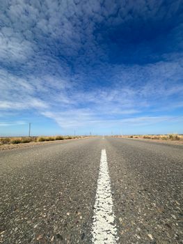 A solitary road stretches through the vast Patagonian landscape under a dramatic sky.