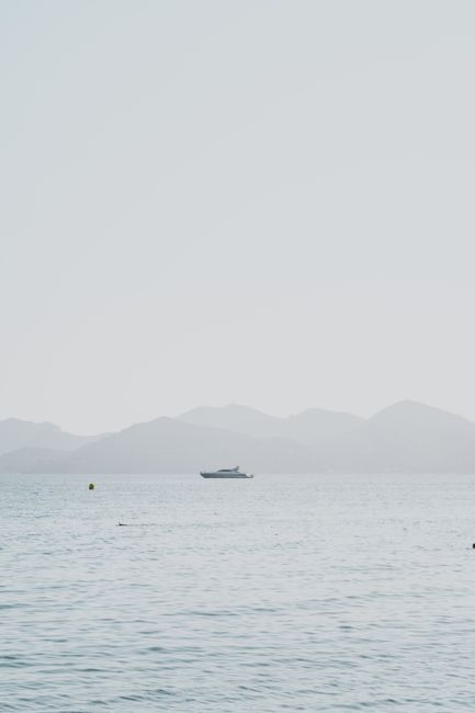 Peaceful scene of a boat on a lake near mountains in Cannes, France.