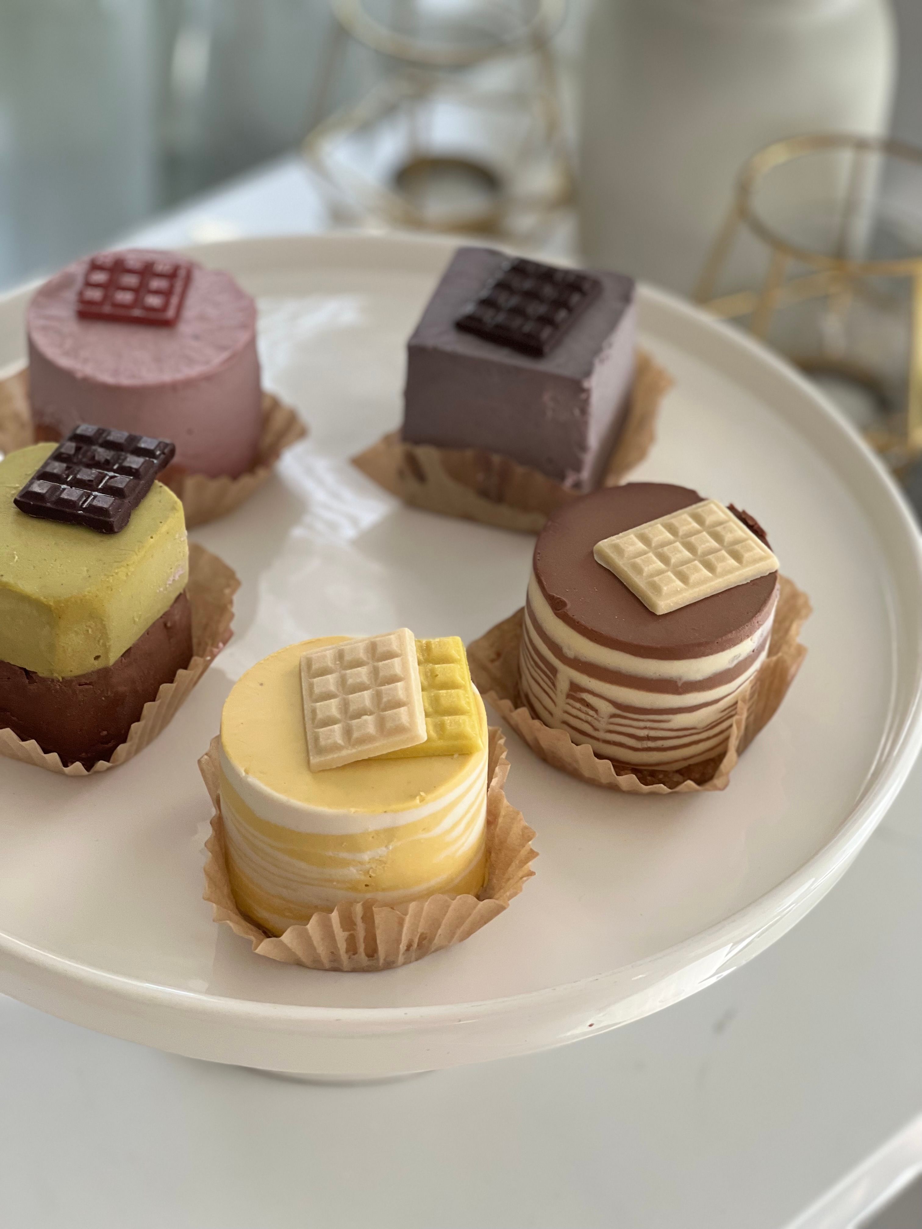 Delicious mousse cakes in various flavors displayed on a white cake stand.