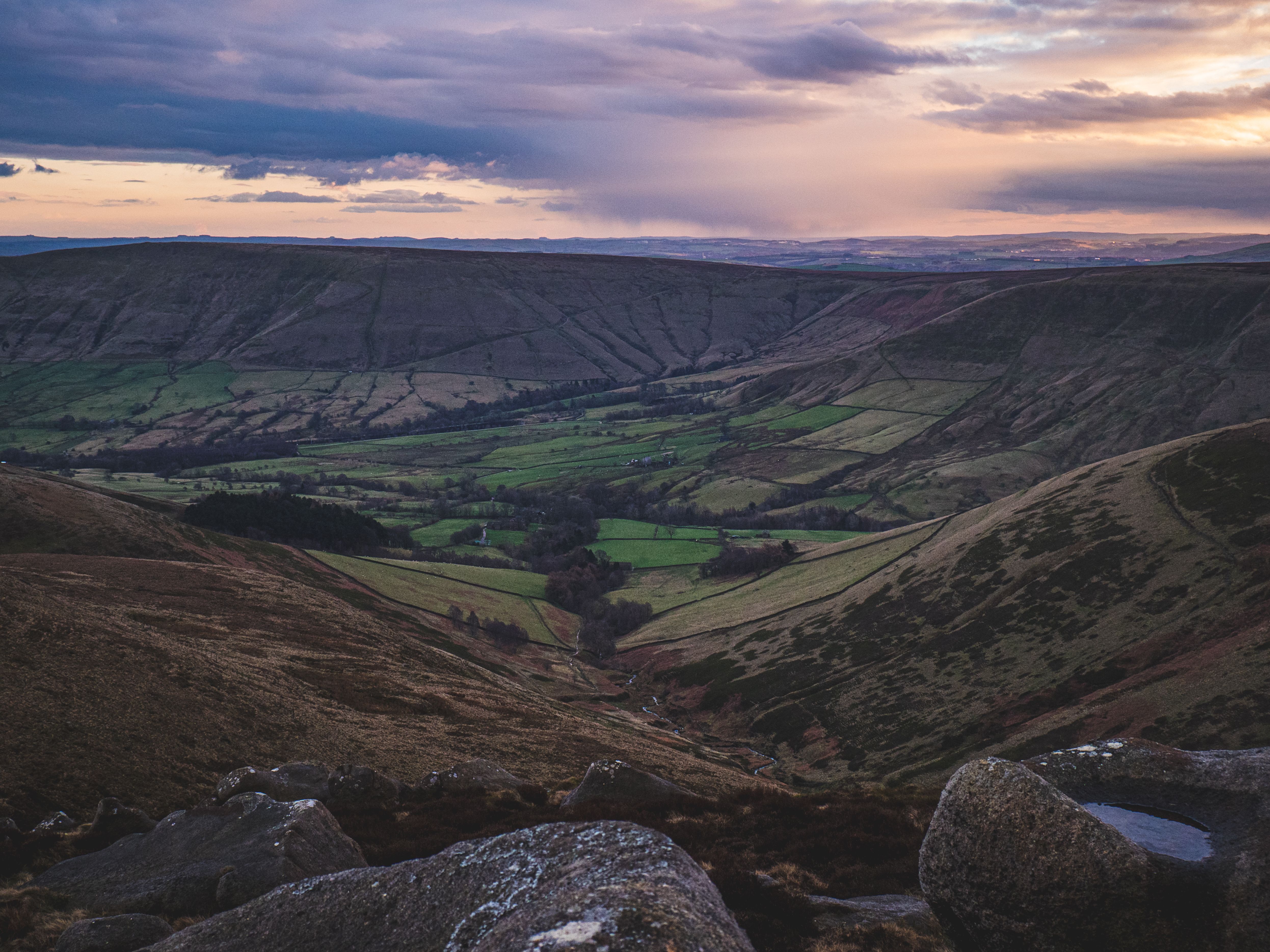 A stunning twilight view over rolling hills and lush green fields in a serene valley landscape.